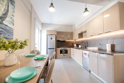 a kitchen with a wooden table and a kitchen with white cabinets at Central apartment 5min from Omonoia Subway Station in Athens