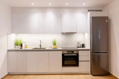 a kitchen with white cabinets and a stainless steel refrigerator at Lighthouse Kipseli in Athens