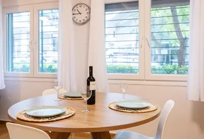 a dining room table with a bottle of wine and a clock at Lighthouse Kipseli in Athens