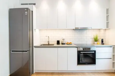 a kitchen with white cabinets and a stainless steel refrigerator at Lighthouse Kipseli in Athens