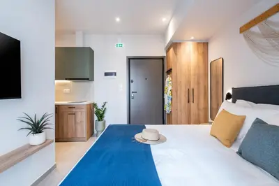 a bedroom with a white bed with a blue blanket at PAME Apartments Athens in Athens