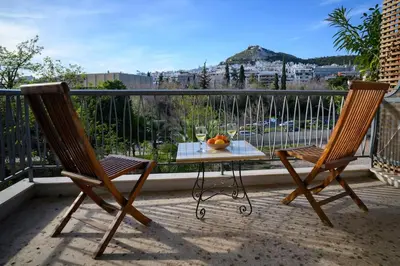 two chairs and a table with a glass of wine on a balcony at Athenian Artistic Apt Lycabettus View in Athens