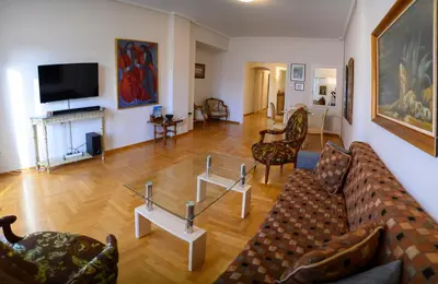 a living room with couches and chairs and a television at Athenian Artistic Apt Lycabettus View in Athens
