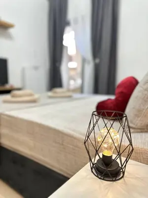 a candle on a table in front of a bed at Arkadia`Kalithea in Athens