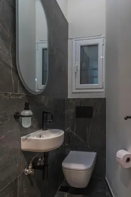 a bathroom with a sink and a toilet and a mirror at Modern Ilisian Apartment in Athens