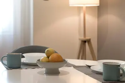 a table with a bowl of fruit and cups on it at Modern Ilisian Apartment in Athens