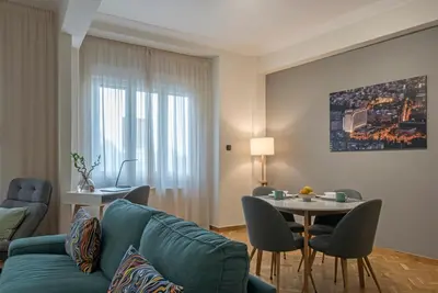 a living room with a blue couch and a table at Modern Ilisian Apartment in Athens