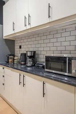 a kitchen with white cabinets and a counter with a microwave at Modern Ilisian Apartment in Athens