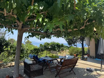 a patio with a table and chairs under a tree at Villieta Marina in Vaia
