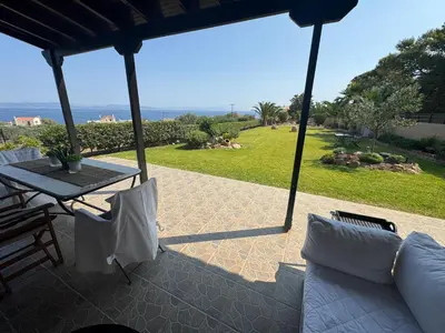a patio with a table and chairs and a view of the ocean at Villieta Marina in Vaia
