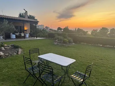 a table and chairs in a yard with the sunset at Villieta Marina in Vaia