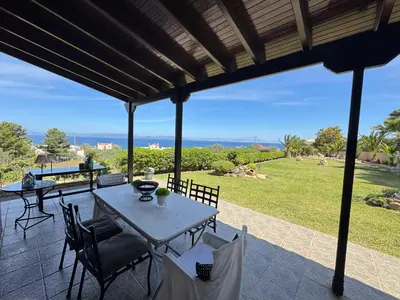 a patio with a table and chairs and a view of the ocean at Villieta Marina in Vaia