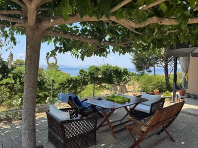 a patio with a table and chairs under a tree at Villieta Marina in Vaia