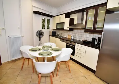 a kitchen with a table and some white chairs at Ifigenias Apartment-Near Acropolis-Koukaki in Athens