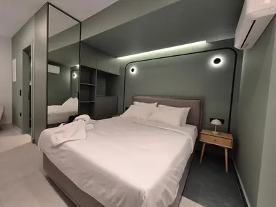 a bedroom with a large white bed and a mirror at By The Stadium in Athens