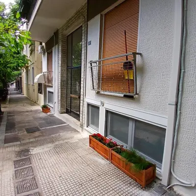 a building with two windows and flowers on a sidewalk at By The Stadium in Athens