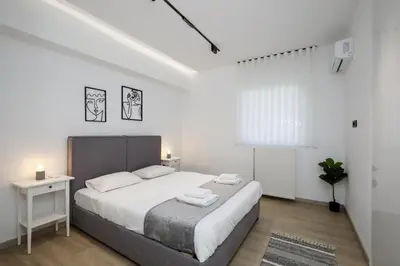 a white bedroom with a large bed and a window at Glyfada Golden Residence - 3 bedroom - Greecing in Athens