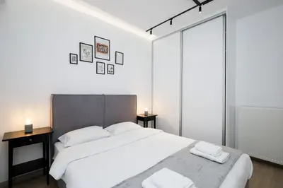 a white bedroom with a large bed and two tables at Glyfada Golden Residence - 3 bedroom - Greecing in Athens