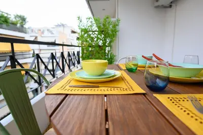 a wooden table with plates and glasses on a balcony at Mesmerizing 2bedroom Luxury in Athens