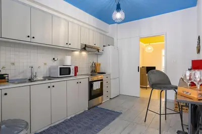 a kitchen with white cabinets and a table and a chair at Mesmerizing 2bedroom Luxury in Athens