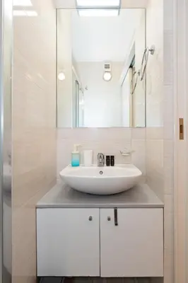 a bathroom with a white sink and a mirror at Minimalist 2-Bedroom Apartment with Balcony in the Heart of Athens in Athens
