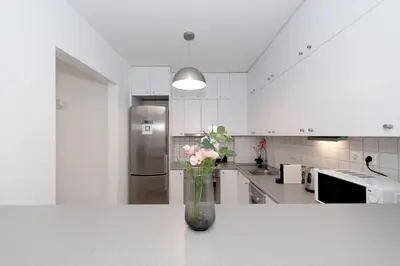 a vase filled with pink flowers sitting on a counter in a kitchen at Minimalist 2-Bedroom Apartment with Balcony in the Heart of Athens in Athens