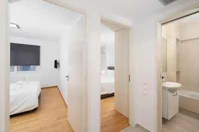 a white bedroom with a bed and a bathroom at Minimalist 2-Bedroom Apartment with Balcony in the Heart of Athens in Athens