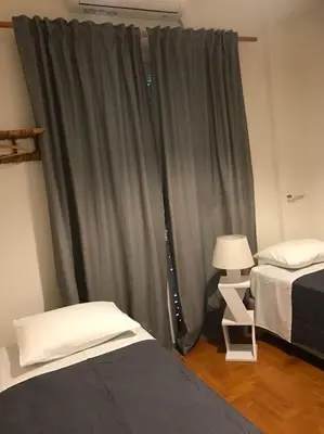 a bedroom with two beds and a curtain at Quiet penthouse at 5th floor in Athens
