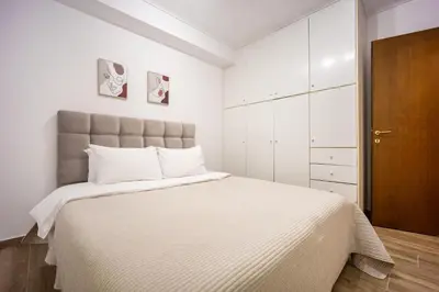 a white bedroom with a large bed and a brown cabinet at Athens Homster in Athens