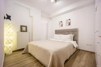 a bedroom with a bed with white walls and wood floors at Athens Homster in Athens