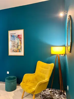 a yellow chair in a room with a blue wall at Elegant apartment in Thissio in Athens