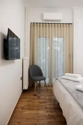 a bedroom with a bed and a chair next to a window at Cozy Apartment in Larisis 9-11 in Athens