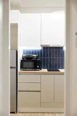 a kitchen with white cabinets and a black microwave at Cozy Apartment in Larisis 9-11 in Athens