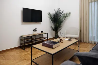 a living room with a table and a tv on a wall at Cozy Apartment in Larisis 9-11 in Athens