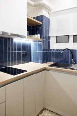 a kitchen with white cabinets and blue tiles at Cozy Apartment in Larisis 9-11 in Athens