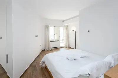 a white bedroom with a bed and a window at Zeus3 Beach Front Appartment, 2 BR, Sea View in Athens