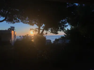 a sunset with a tree in front of a building at Modern Studio - Terrace & Seaview - Close to Beach in Saronida