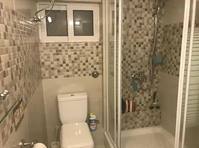 a small bathroom with a toilet and a shower at Modern Studio - Terrace & Seaview - Close to Beach in Saronida