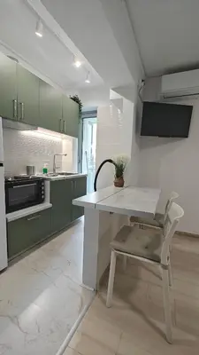 a kitchen with green cabinets and a white table and a chair at Inspire Apartment Palaio Faliro in Athens