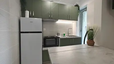 a kitchen with green cabinets and a white refrigerator at Inspire Apartment Palaio Faliro in Athens