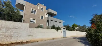 a building with a concrete wall next to a street at Gianni & Sophia airport house in Artemida