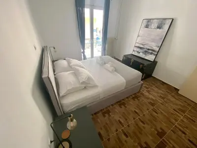 a bedroom with a bed with white sheets and a mirror at Koukaki comfortable apartment in Athens