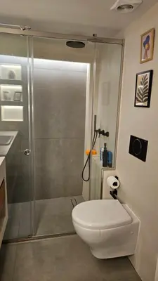 a bathroom with a shower and a white toilet at Heart of Faliro 2BR 5m Walk to Beach - Newly Renovated in Athens