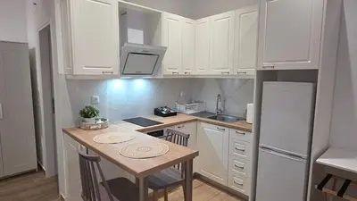 a kitchen with white cabinets and a small table at Central Lux Lining B in Athens