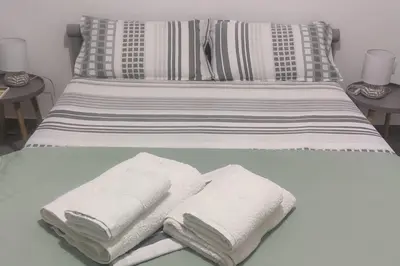 a bed with white towels on it with two tables at Comfortably placed near the sea in Saronida