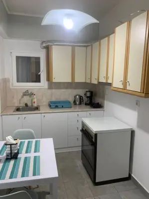 a kitchen with white cabinets and a black appliance at Comfortably placed near the sea in Saronida