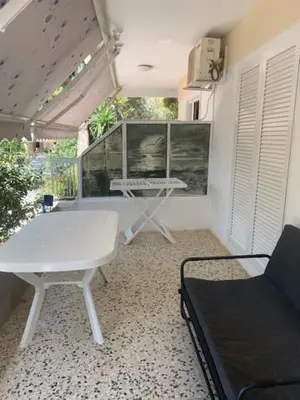 a living room with a white table and a bench at Comfortably placed near the sea in Saronida