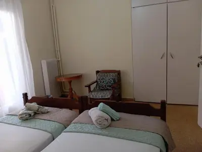 a bedroom with two twin beds and a chair at ROOM 2 single beds 5' from metro in Athens