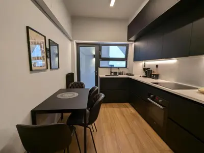 a kitchen with black cabinets and a table and chairs at Momentum Apartment in Athens