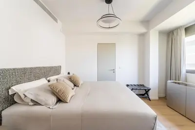 a white bedroom with a large white bed with pillows at Glyfada Gem - 3BD apartment in Athens